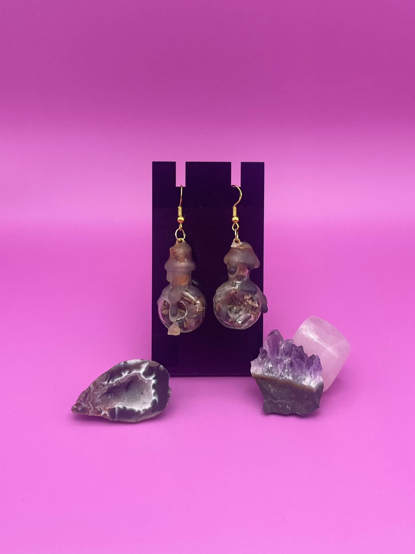 protective spell earrings on black stand with purple background