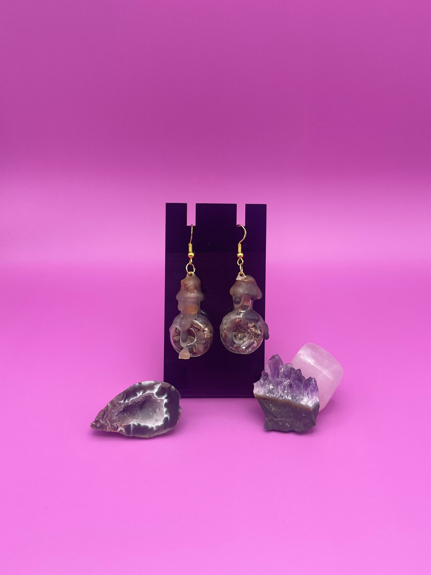 protective spell earrings on black stand with purple background