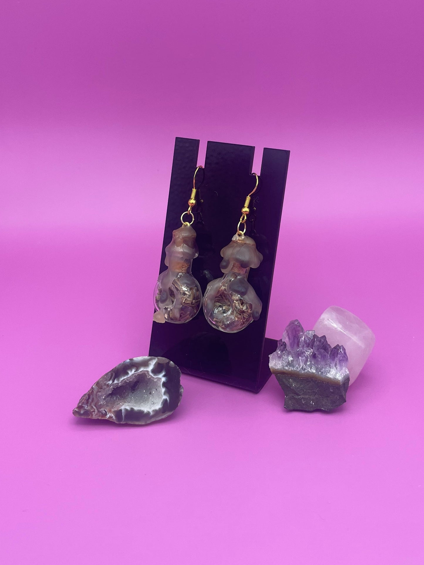 Protection spell earring on black stand with purple background