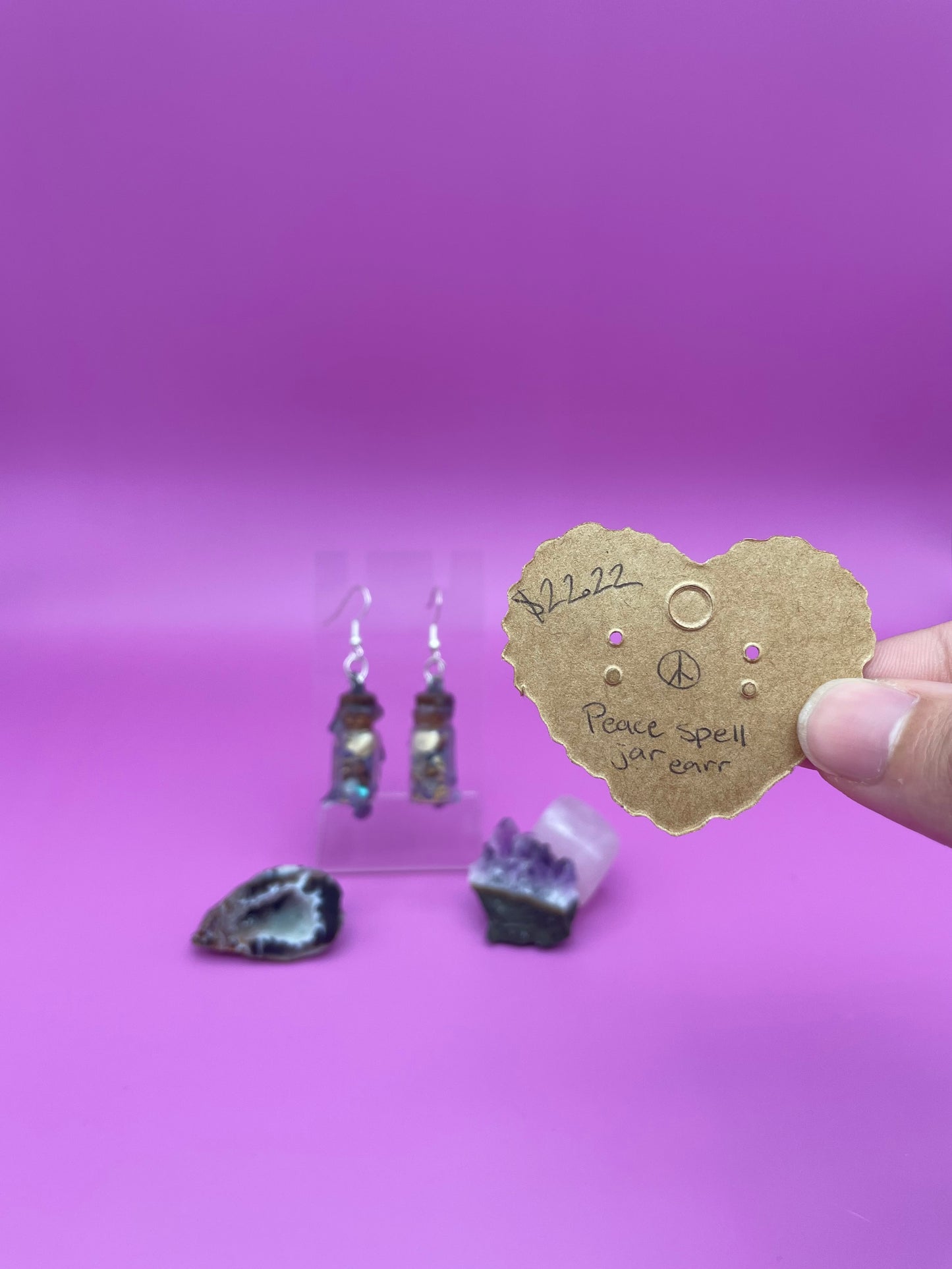 Peace spell jar earrings on clear stand