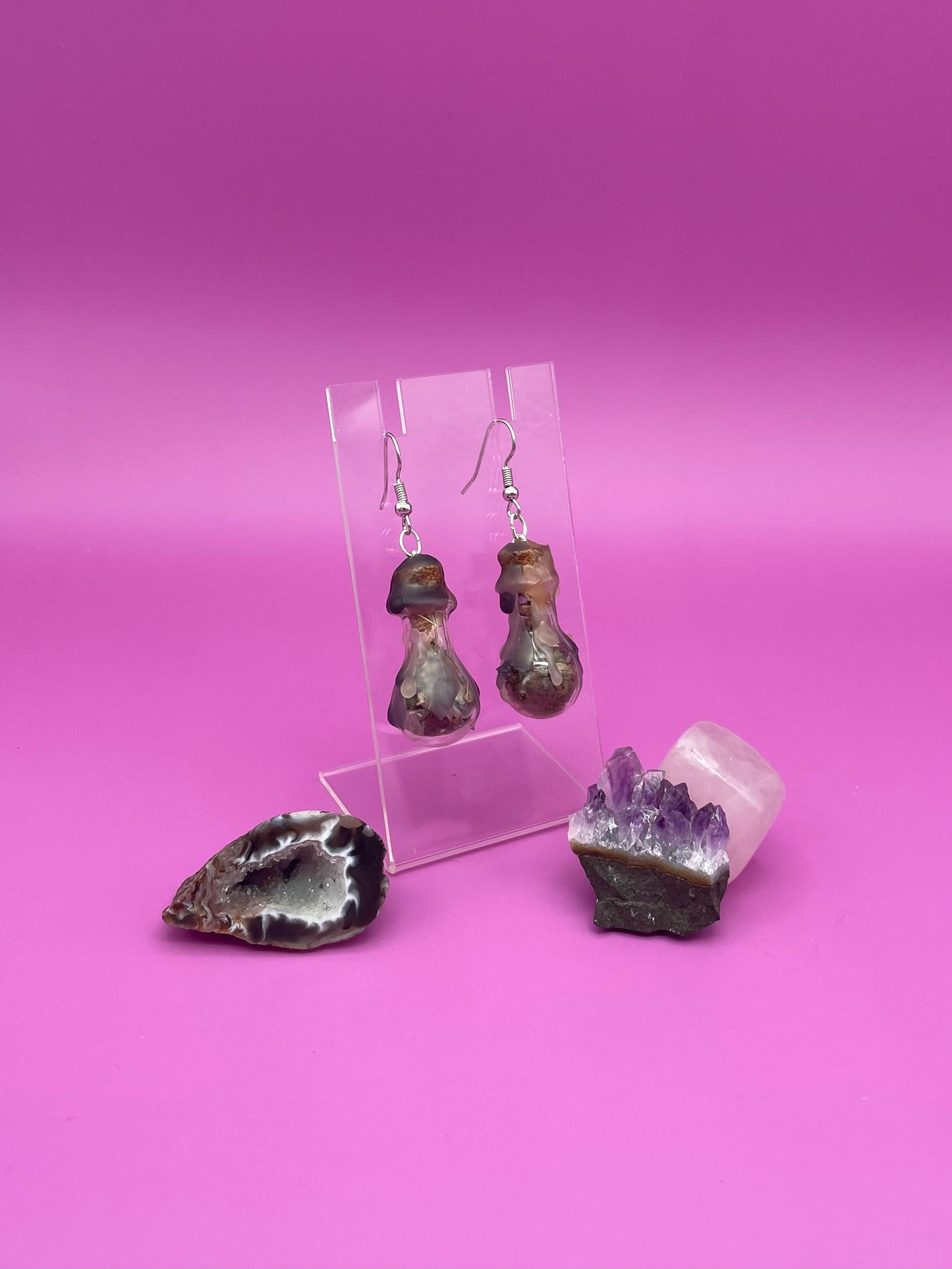 Protection spell earrings on clear stand with purple background