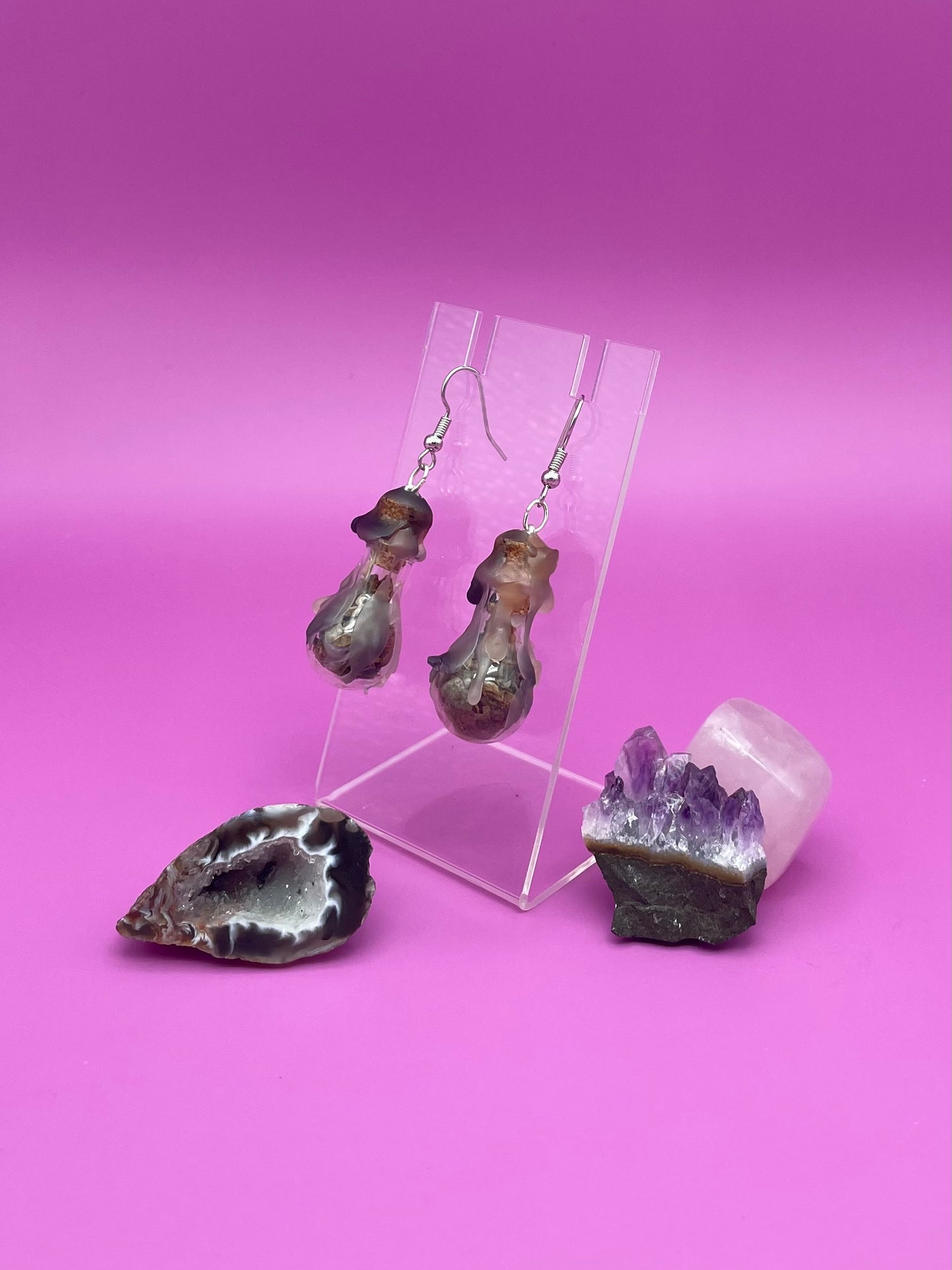 Protection spell earrings on clear stand with purple background