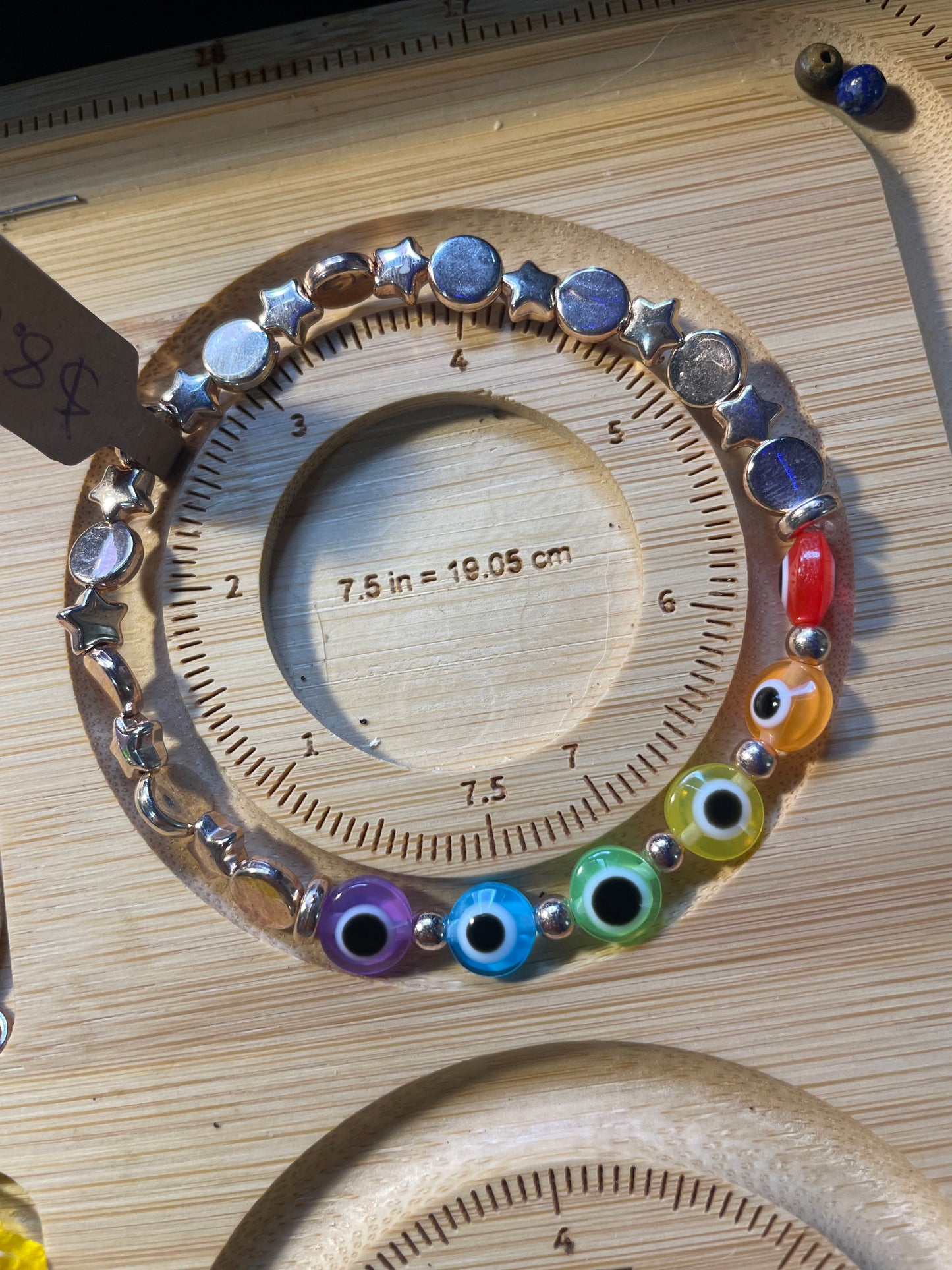 Rose Gold and rainbow evil eye bracelet on sizing board, 7.5in