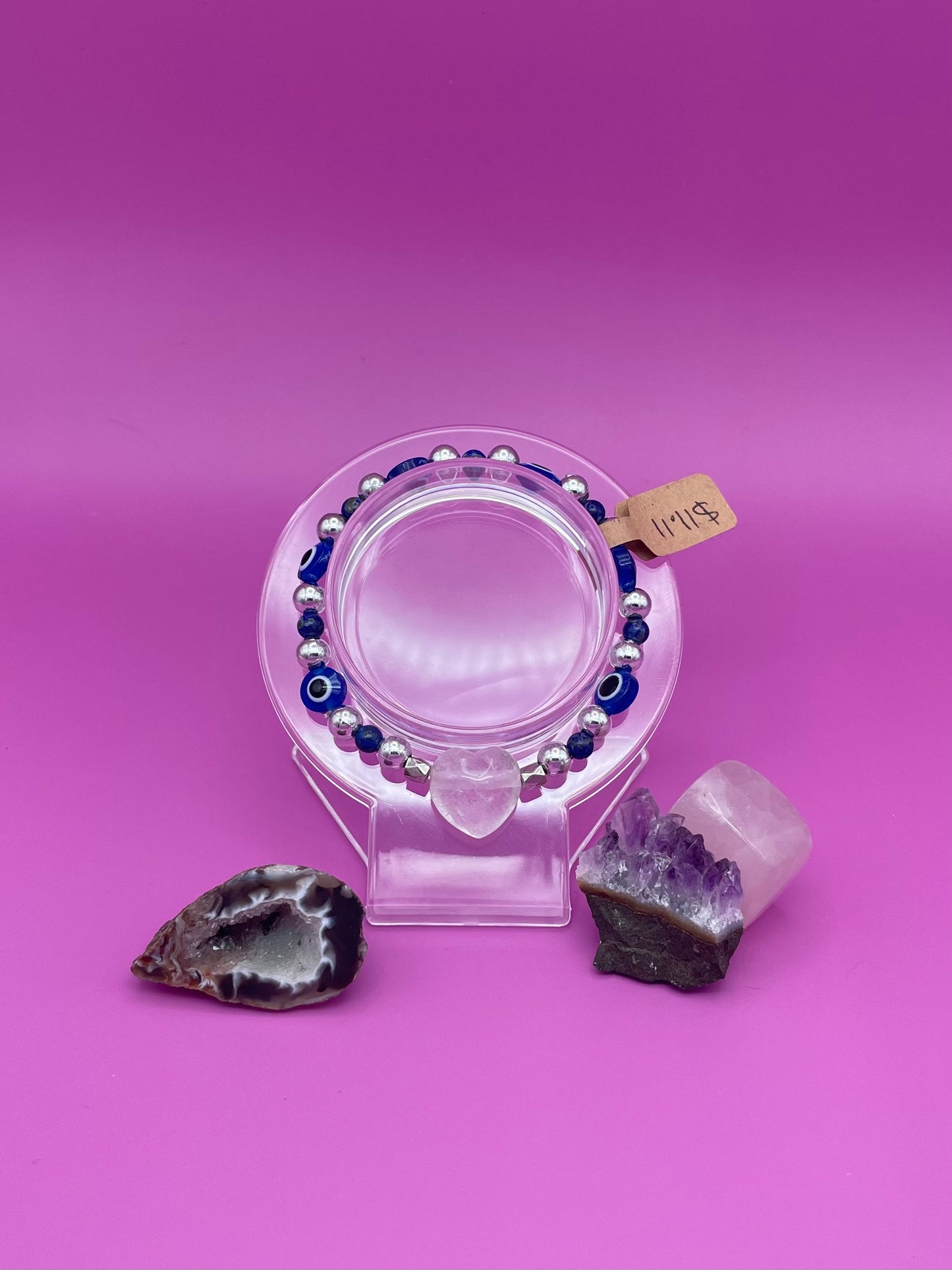 Blue and silver evil eye bracelet with clear quartz crystal centerpiece on clear stand