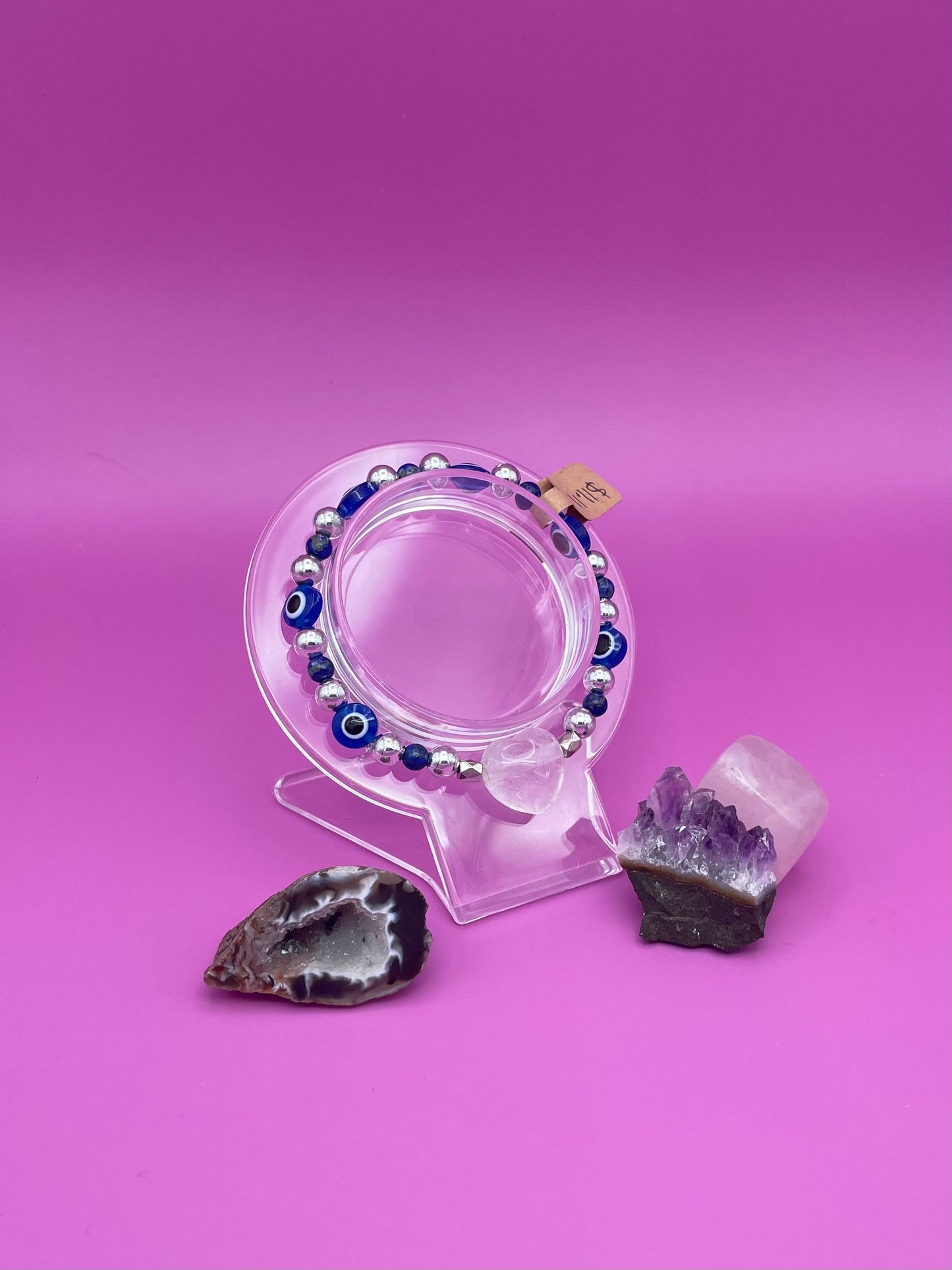 Blue and silver evil eye bracelet with clear quartz crystal centerpiece on clear stand
