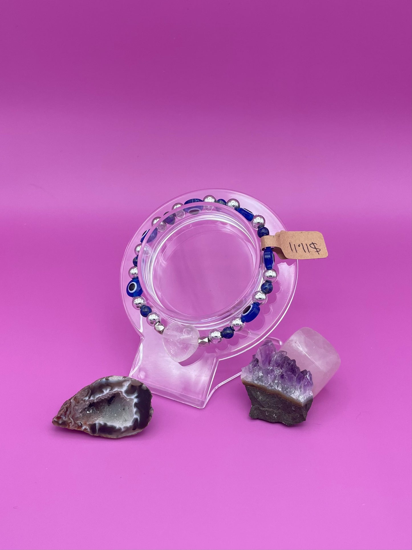 Blue and silver evil eye bracelet with clear quartz crystal centerpiece on clear stand