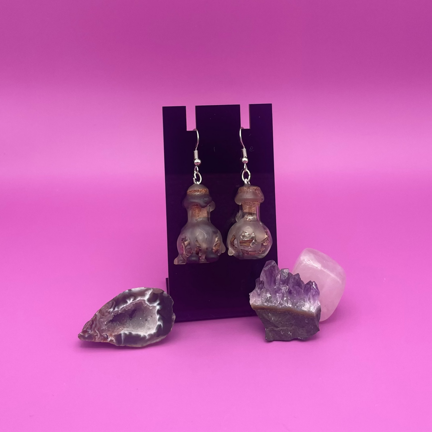 protective spell earrings on black stand with purple background