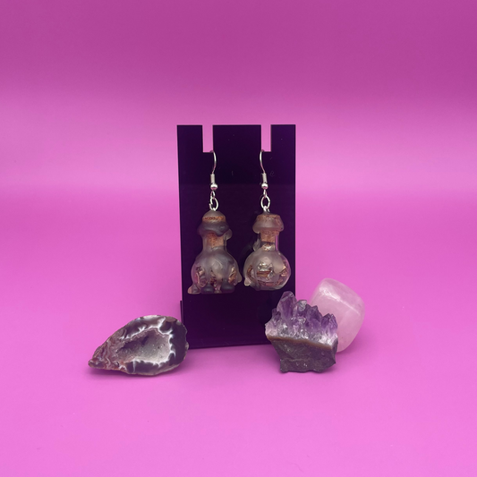 protective spell earrings on black stand with purple background 