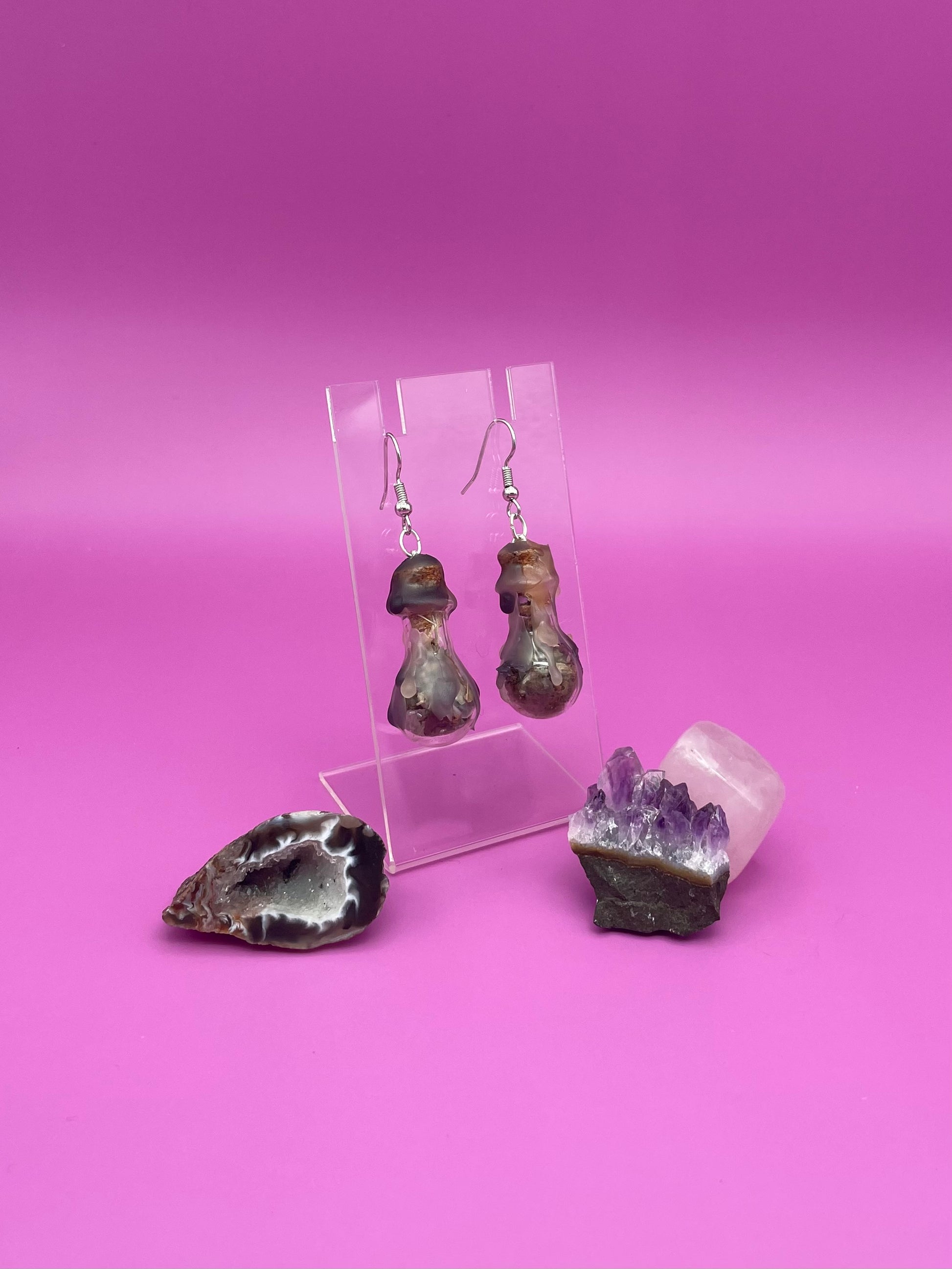 Protection spell earrings on clear stand with purple background