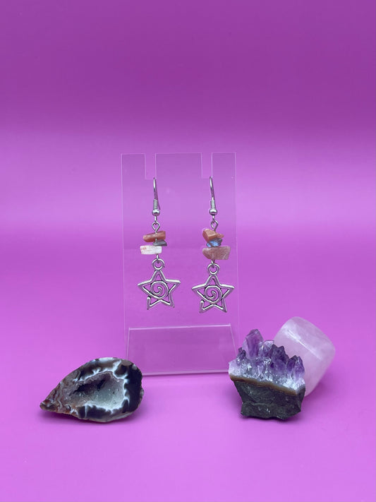 Star-shaped swirl earrings on a clear stand with amethyst crystal and a purple background
