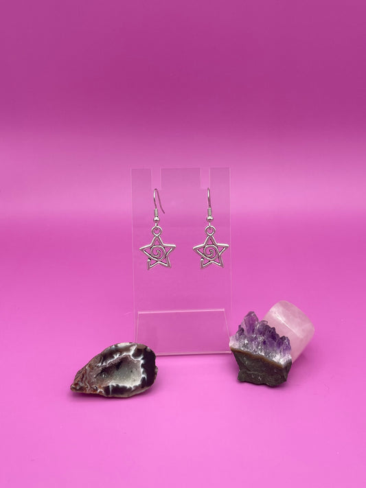 Silver Star-shaped swirl earrings on a clear stand with purple background