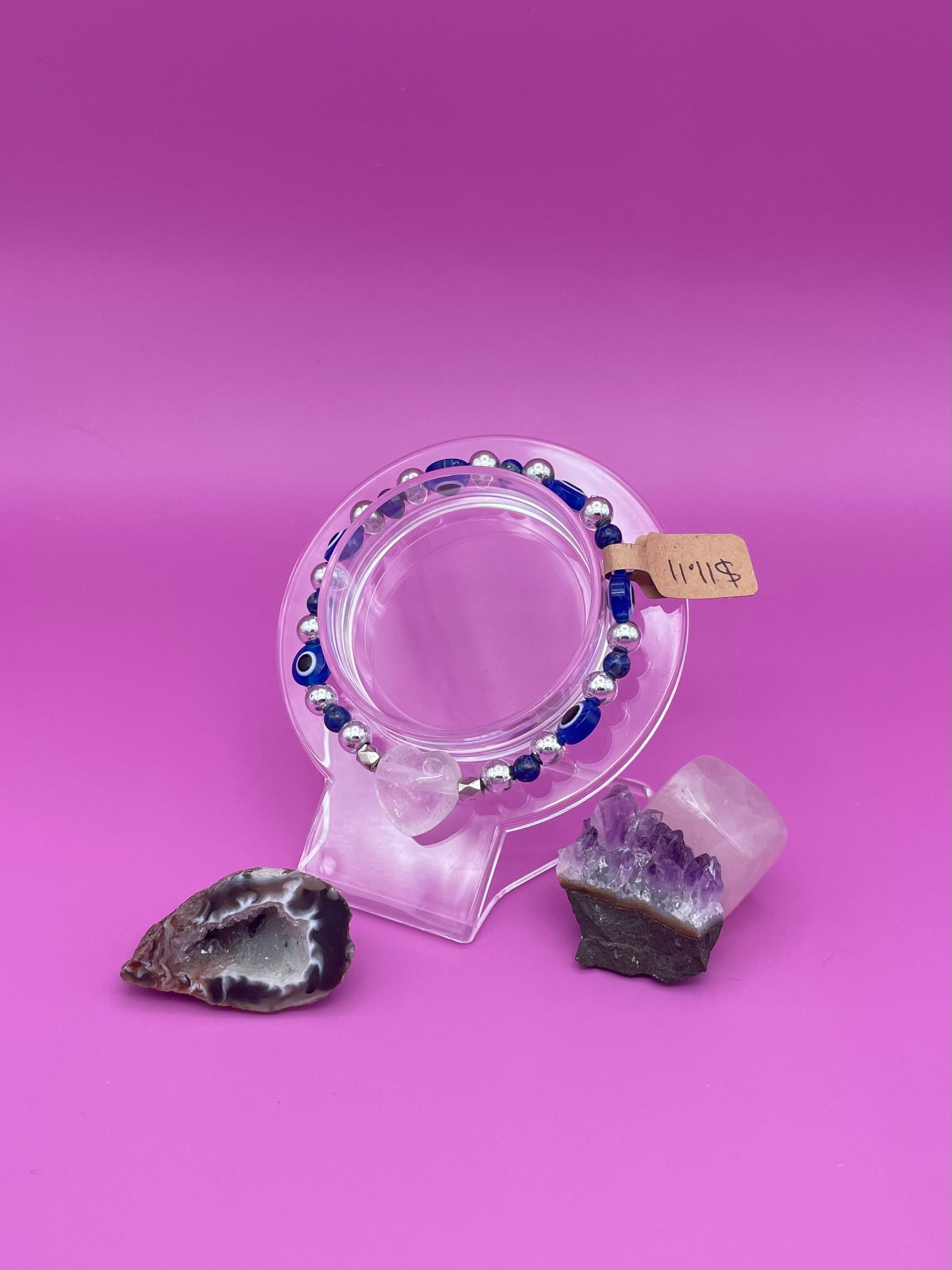 Blue and silver evil eye bracelet with clear quartz crystal centerpiece on clear stand