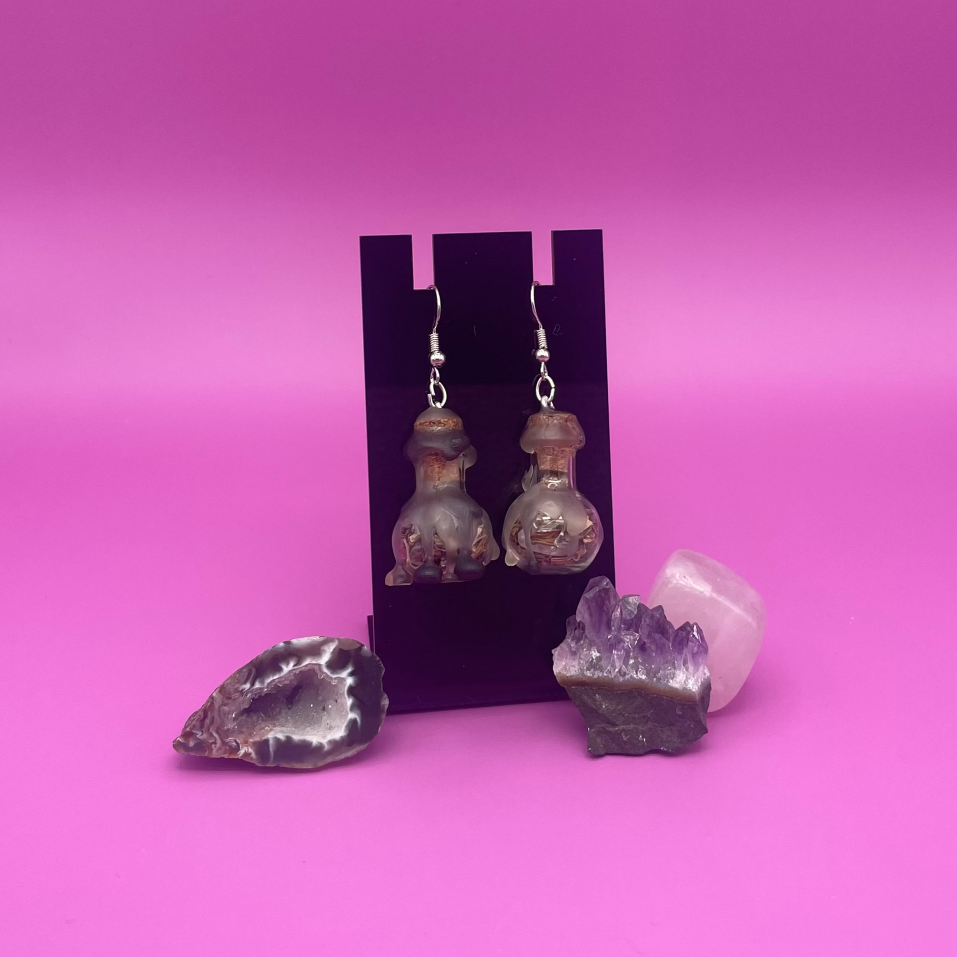 protective spell earrings on black stand with purple background 